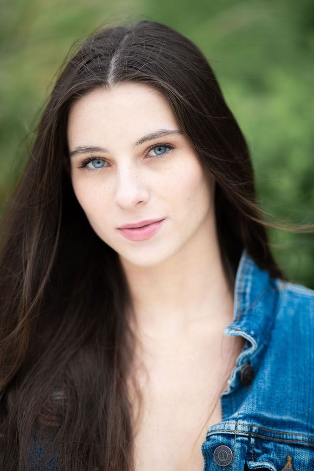 a woman with long dark hair wearing a blue denim shirt