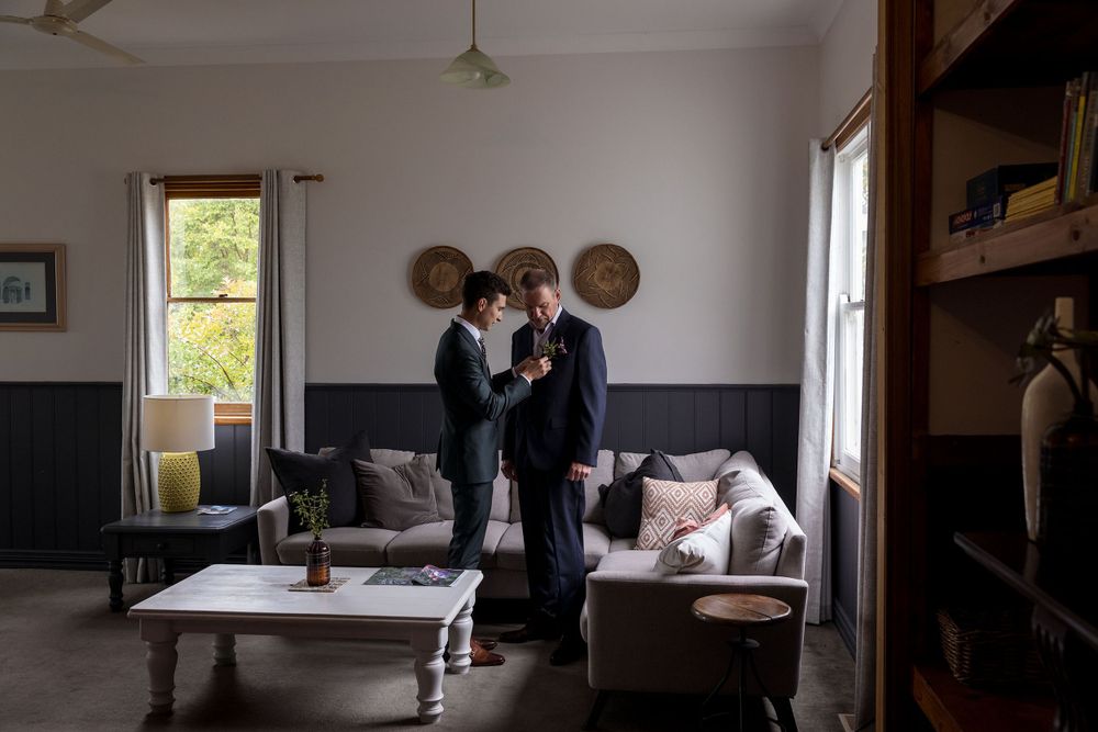 Groom in a Green wedding suit helping his Dad with his button hole flower before his St.Leonards Vineyard winery wedding