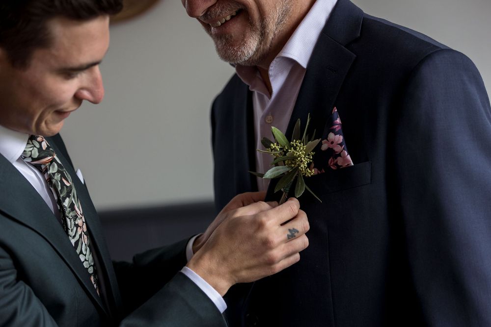 Groom in a Green wedding suit helping his Dad with his button hole flower before his St.Leonards Vineyard winery wedding