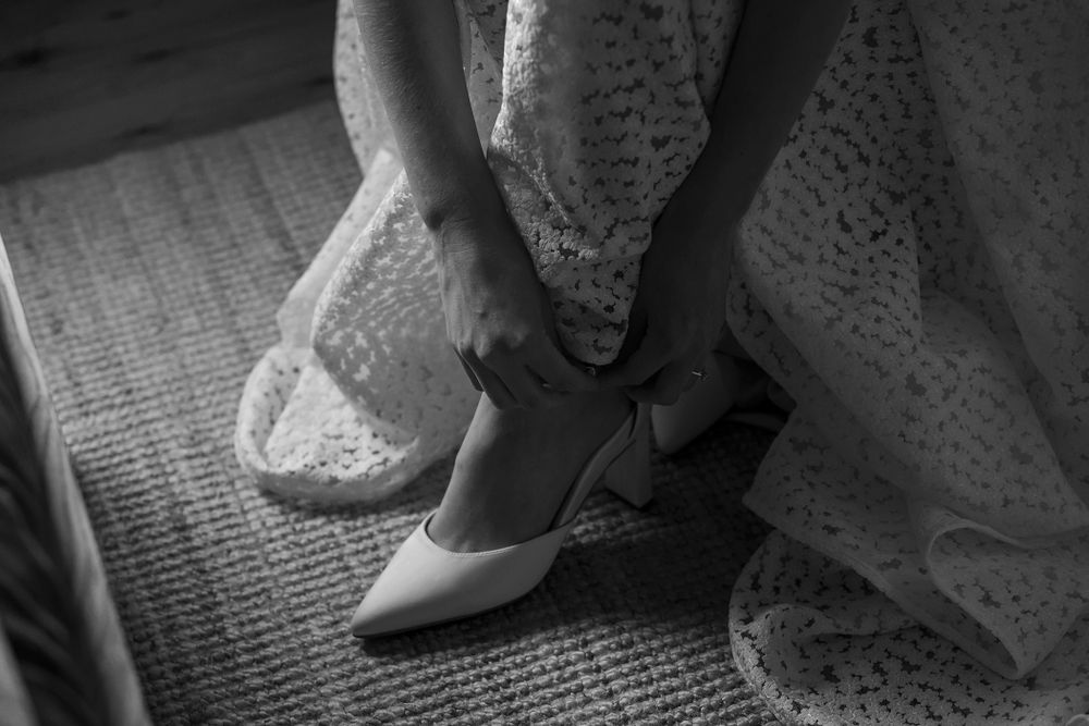 Bride in her wedding dress putting on her wedding shoes before her wedding ceremony at St.Leonards Vineyard