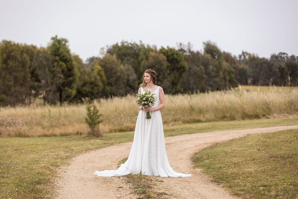 Bride in her wedding dress holding her white flower bouquet before her wedding ceremony at St.Leonards Vineyard