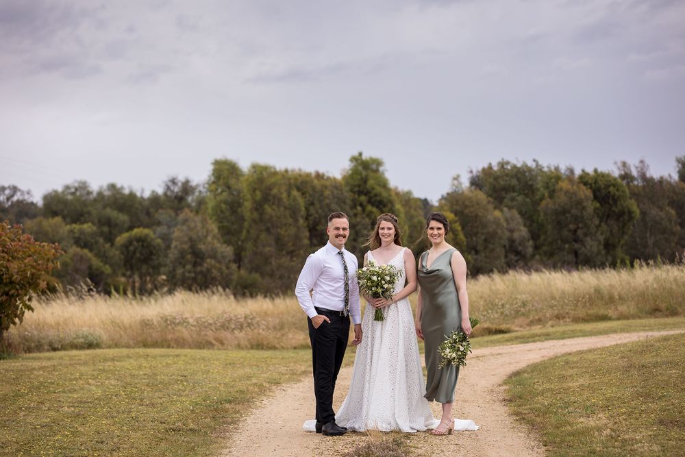 Bride in her wedding dress holding her flower bouquet with her Maid of Honour and Bridesman before her wedding ceremony
