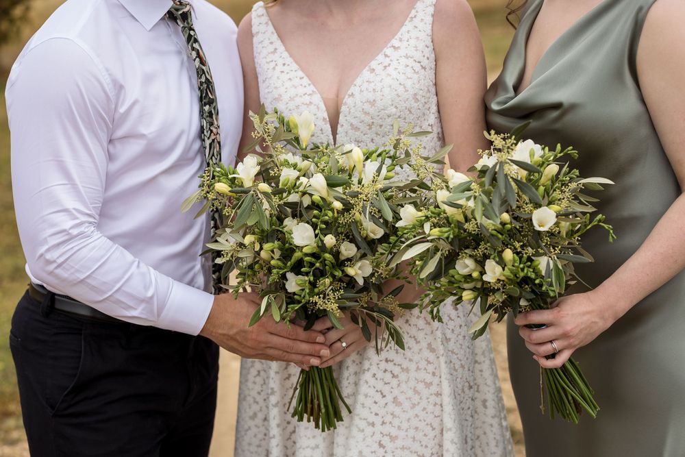 Bride in her wedding dress holding her flower bouquet with her Maid of Honour and Bridesman before her wedding ceremony