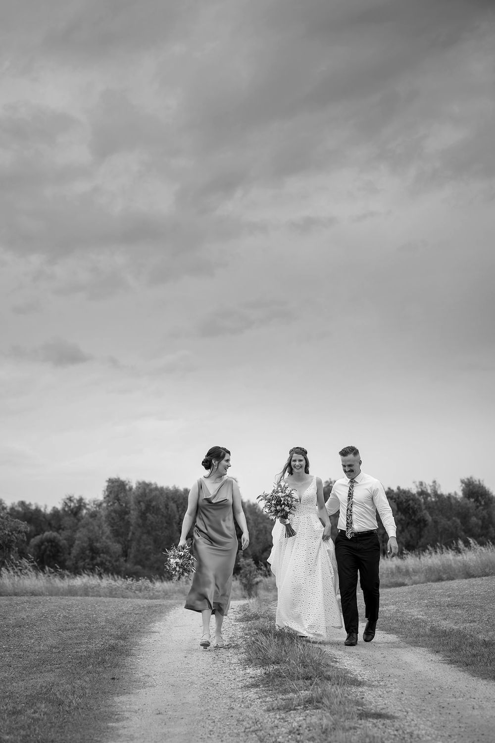 Bride in her wedding dress holding her flower bouquet with her Maid of Honour and Bridesman before her wedding ceremony