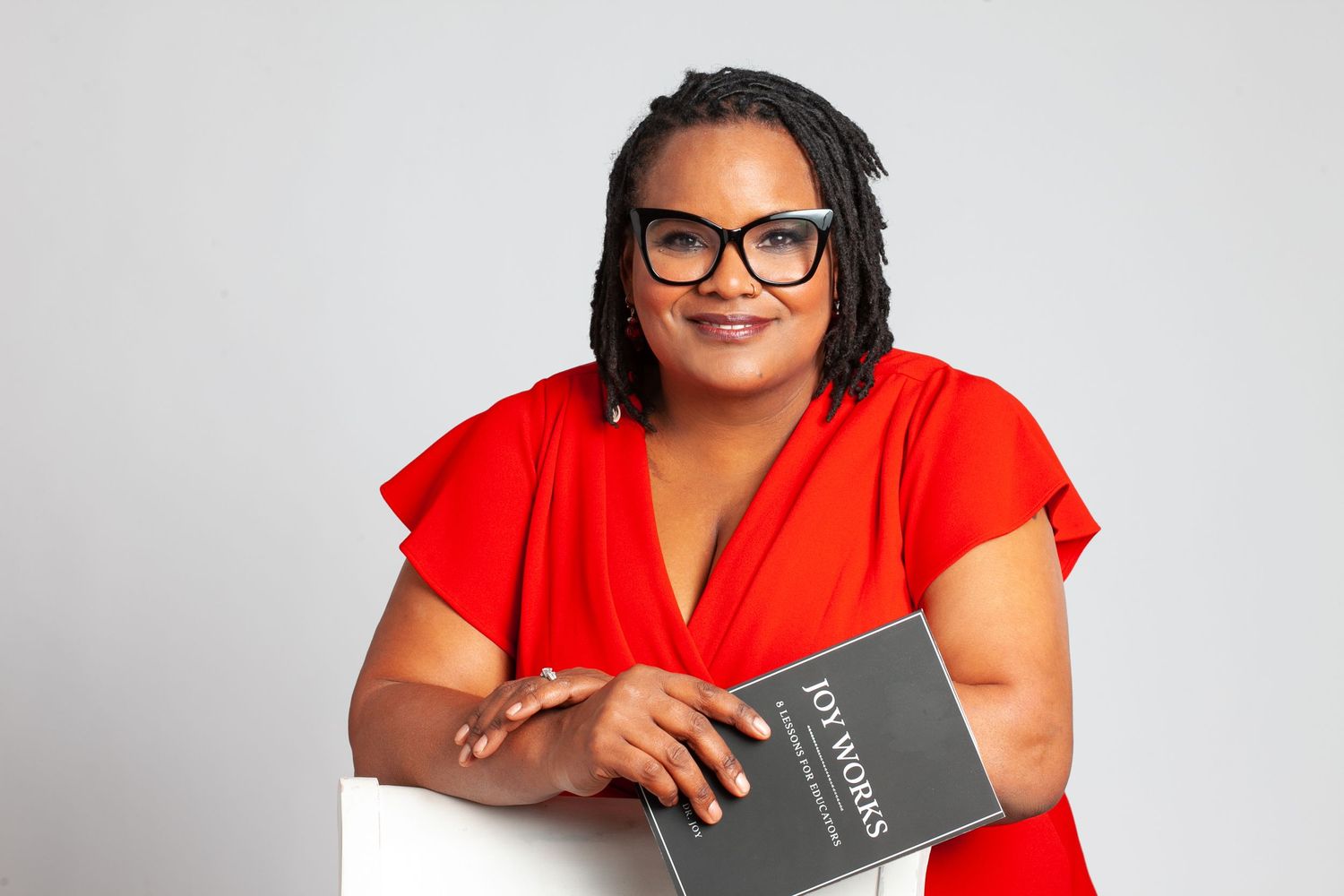 Dr. Joy's headshot to promote her new book. She's wearing a red dress and black glasses.
