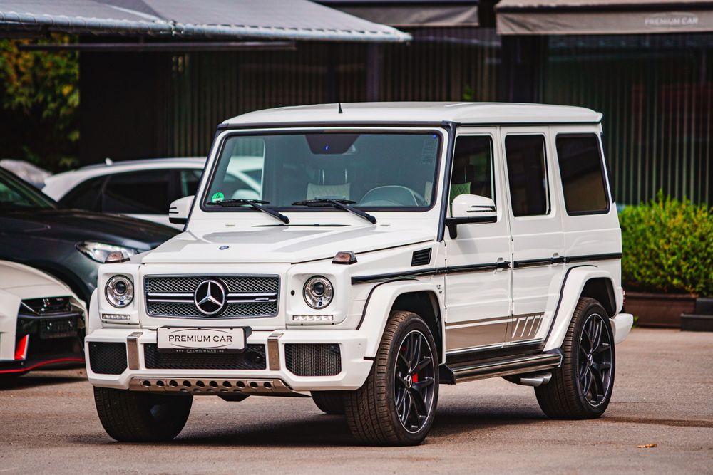 White Mercedes-Benz G-Class SUV with custom wheels parked in front of a building.