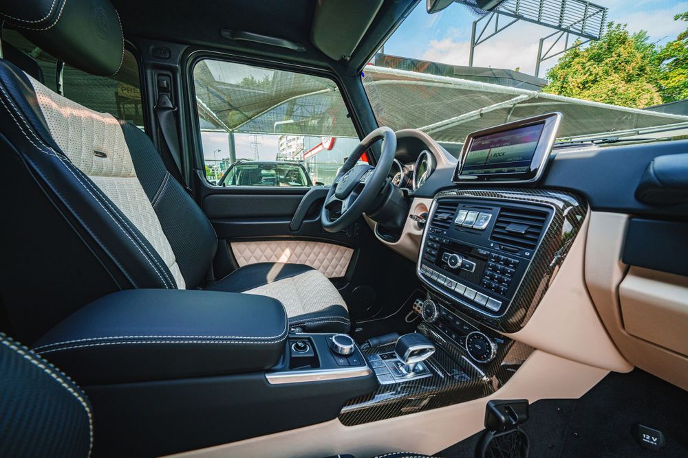 Modern dashboard and center console of Mercedes G-Class with leather and beige accents.