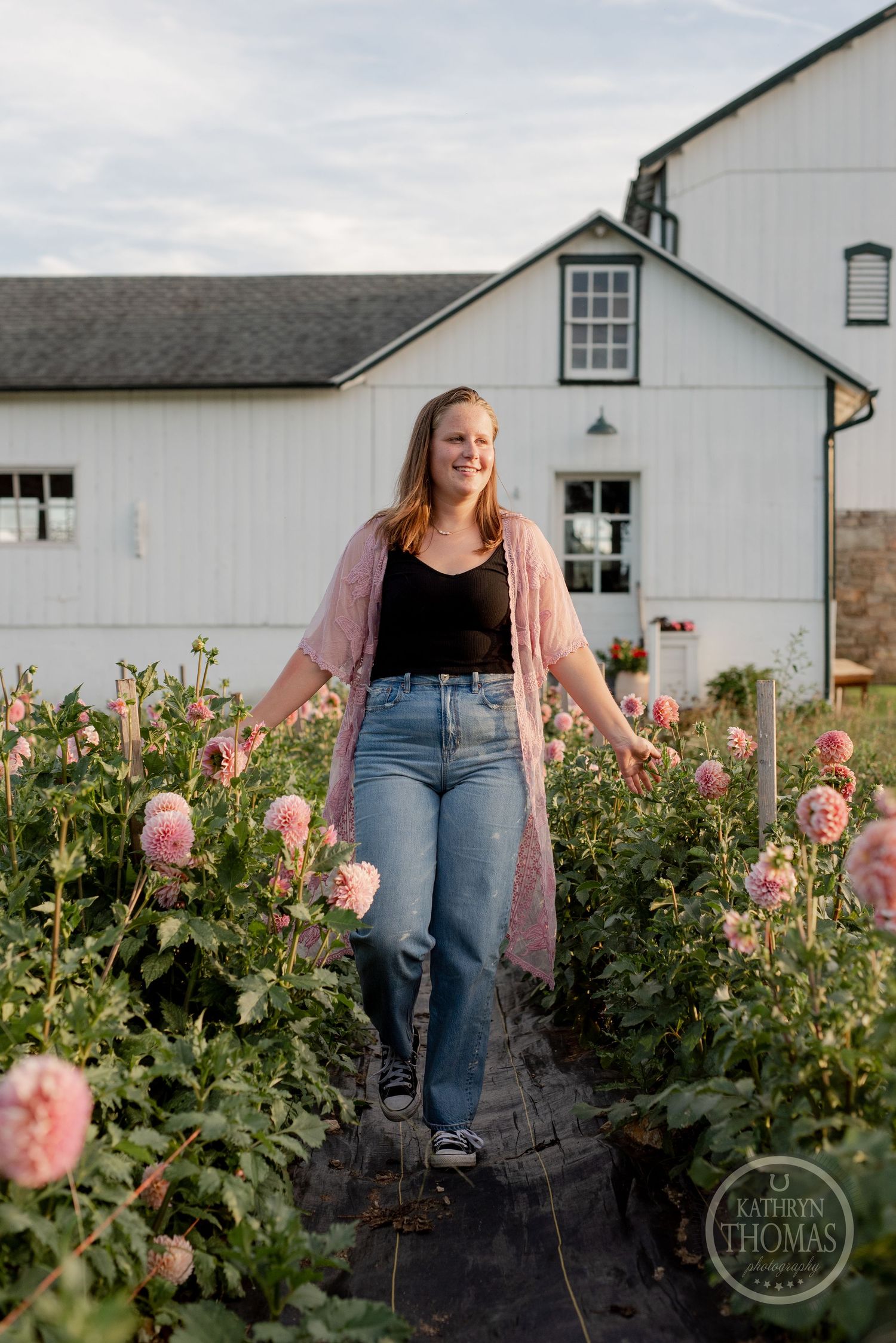 A casual pose in front of a white barn surrounded by pink garden roses.