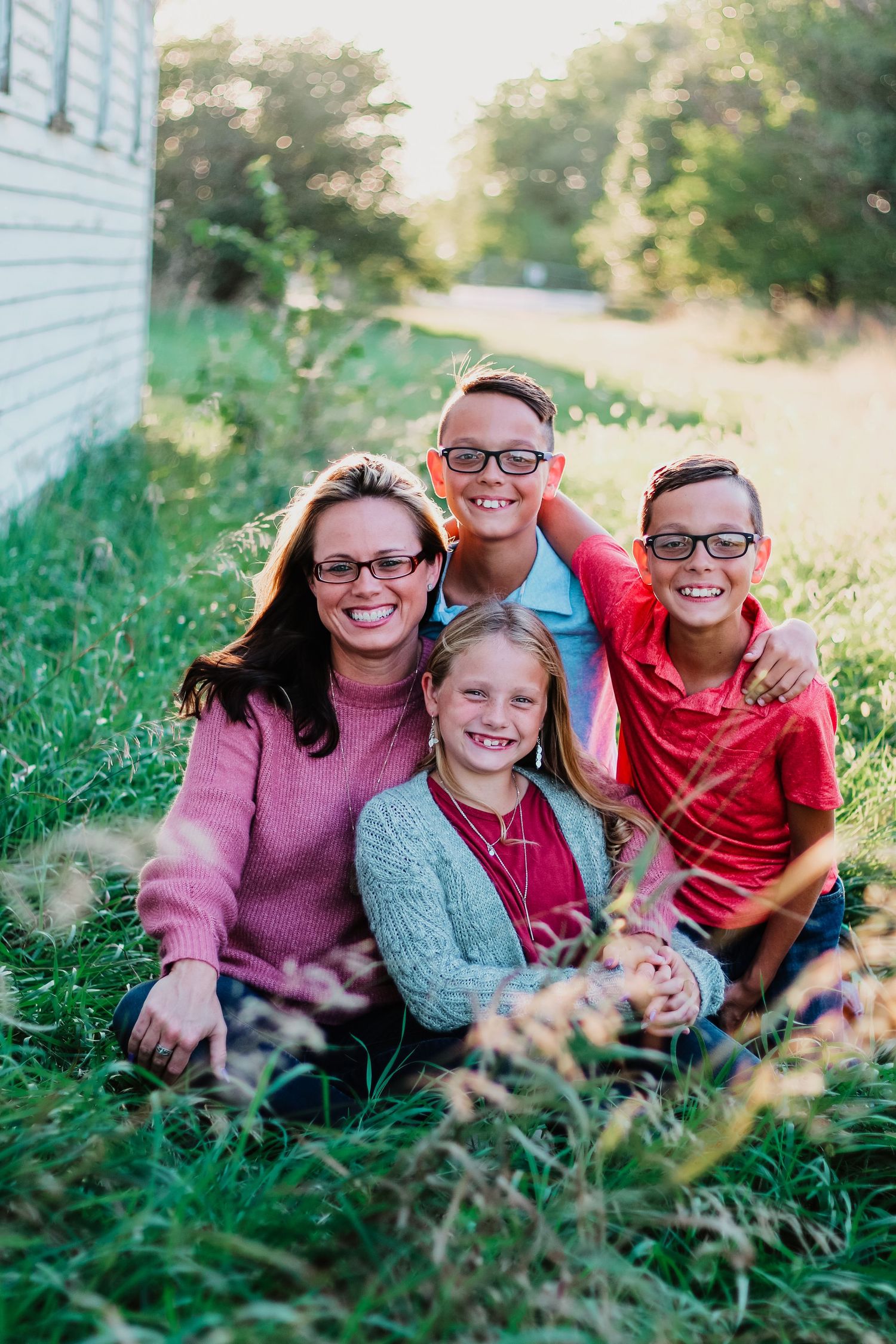 A happy family lounges together in green grass outside their home on a sunny day.