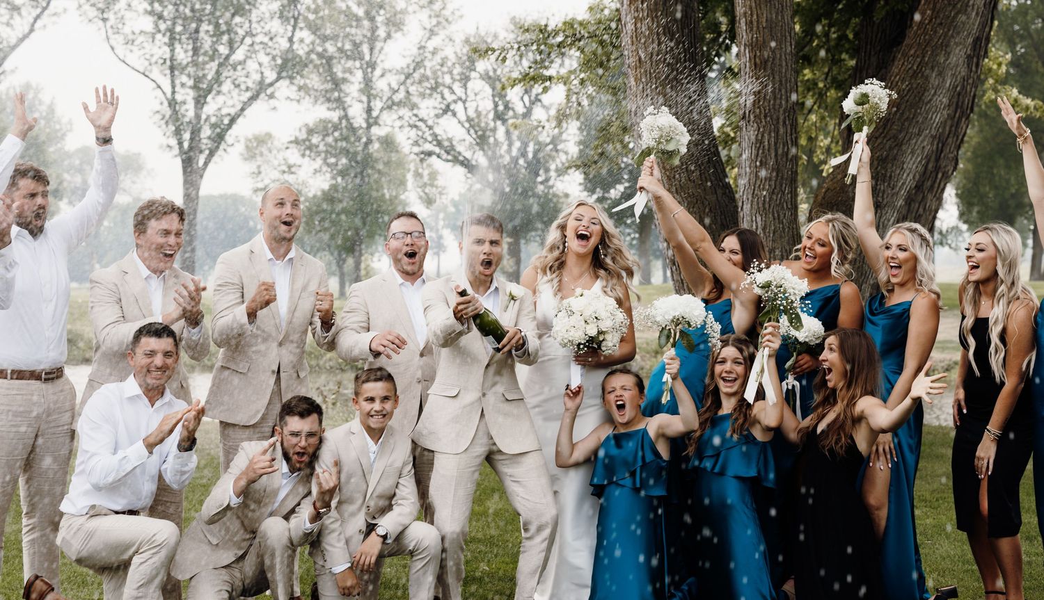 Wedding party celebrating with confetti and cheers in outdoor setting.