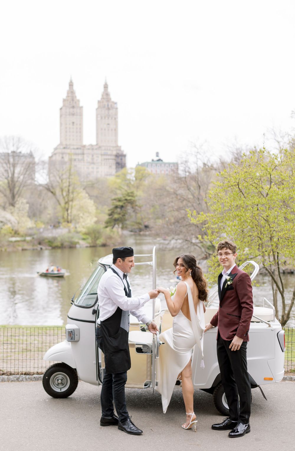 A wedding scene with vintage vehicles and Central Park buildings in the background.