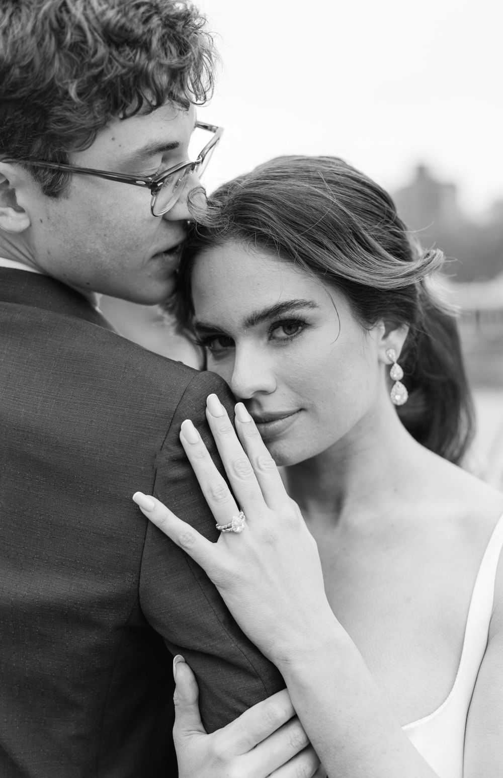 A romantic close-up portrait in black and white showing an engagement ring.