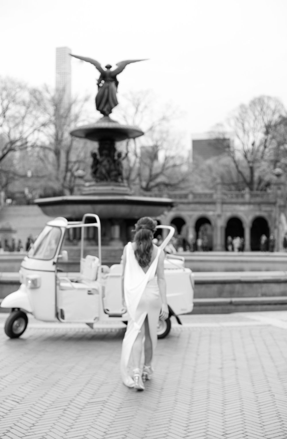 A romantic black and white photo near Bethesda Fountain with a white tuk tuk vehicle.
