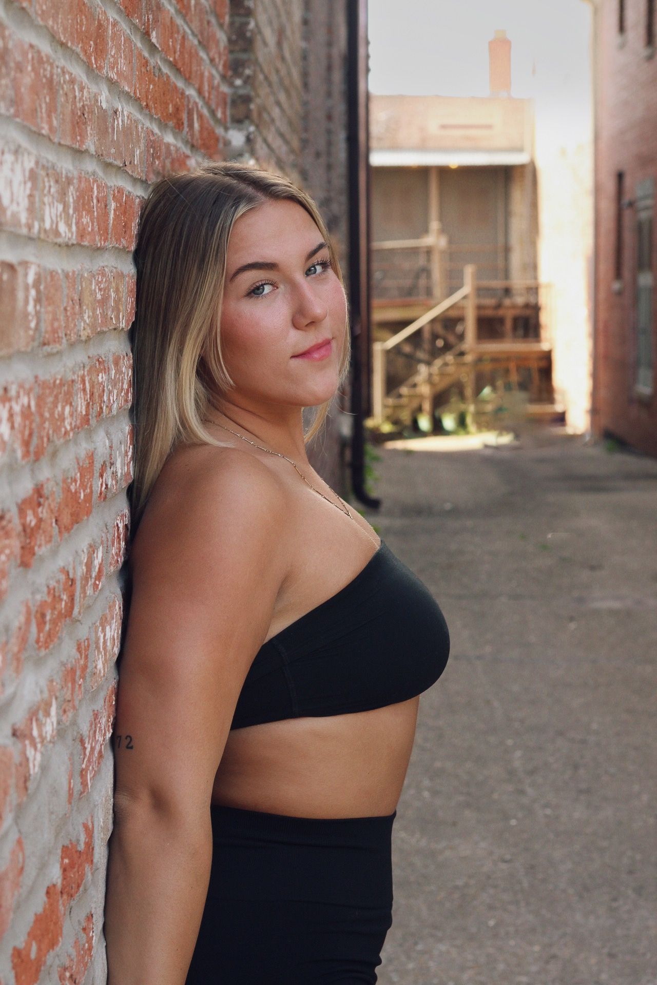 A young woman in a workout set for a branding session in an old alley way for rustic aesthetic photos