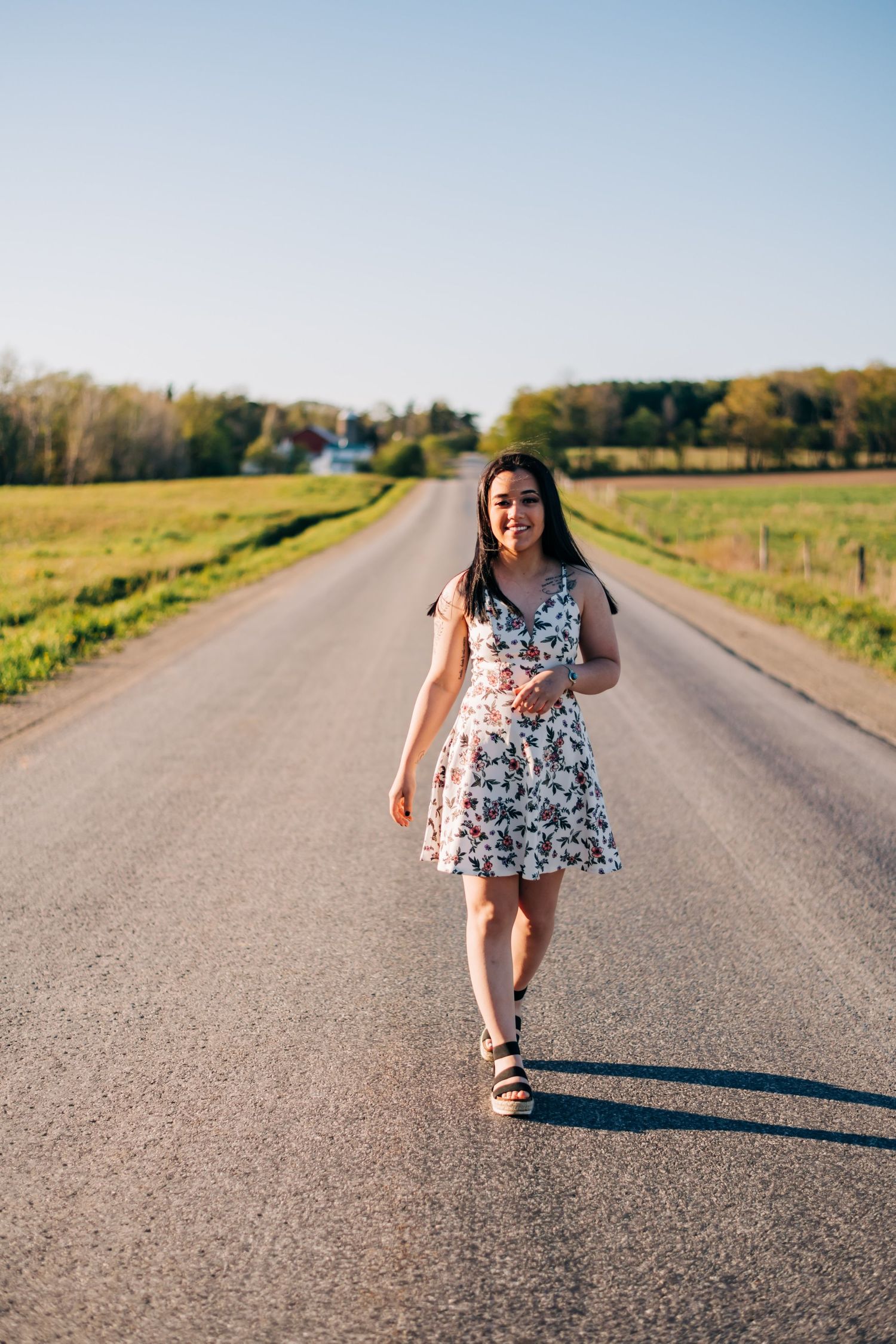 high school senior wearing a white dress walking down a dirt road