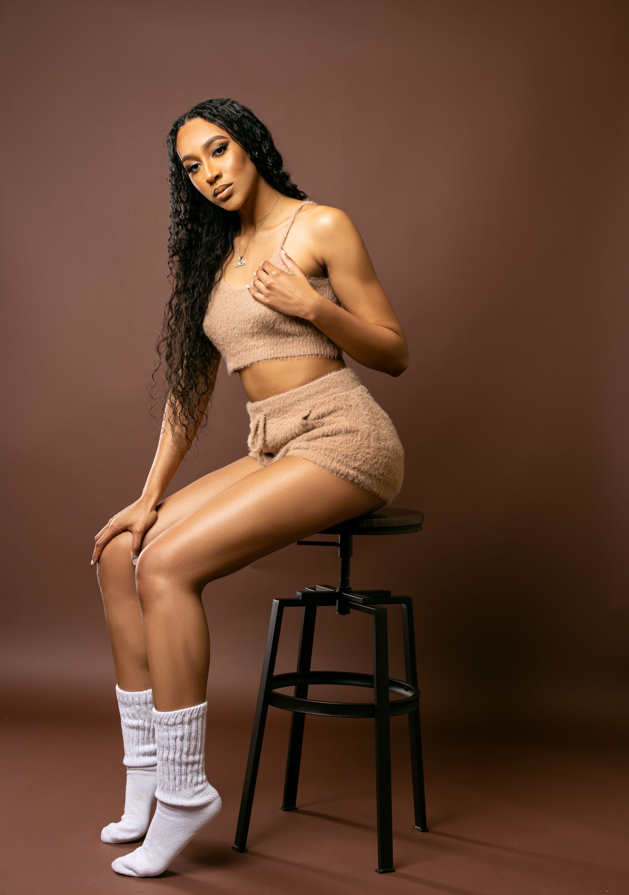 Artistic studio photo in beige loungewear against warm brown backdrop.