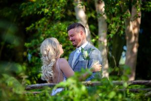 Bride and groom sharing a romantic moment surrounded by lush green foliage at their outdoor wedding.