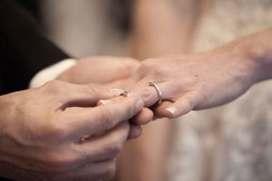 Close-up of groom placing a wedding ring on the bride's finger during the wedding ceremony.