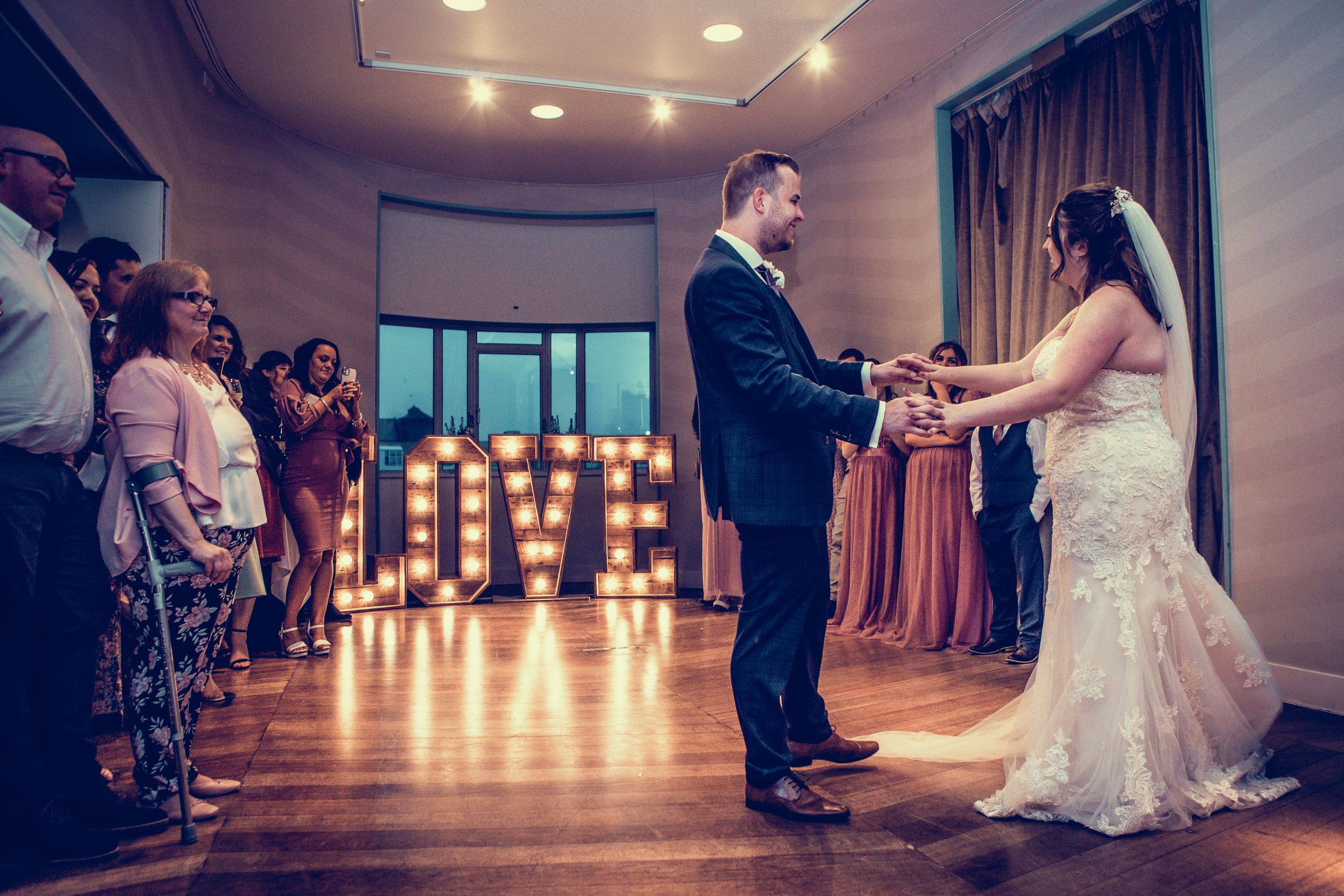 Bride and groom sharing their first dance in front of illuminated LOVE letters at their wedding reception.