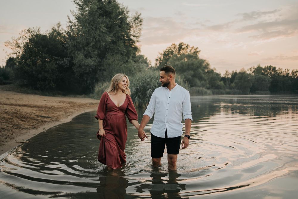 para spaceruje za rękę brzegiem jeziora -  fotograf ciążowy Kraków