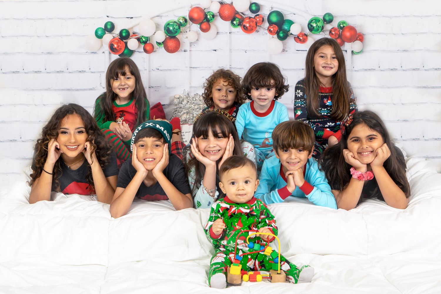 Group of children lying down and posing for holiday photo with festive red and green balloon decorations.