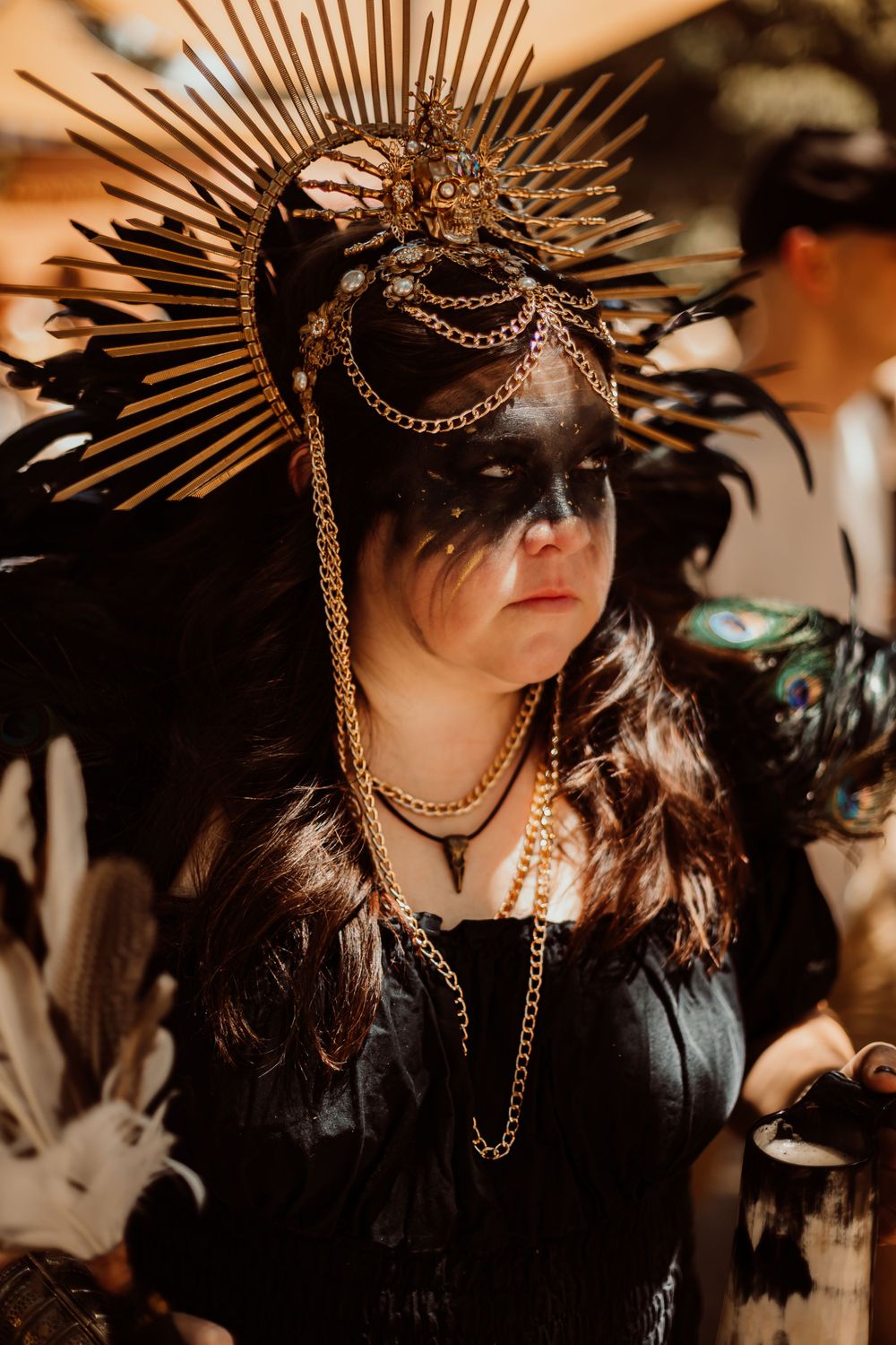 Gothic cosplay look featuring dramatic spiked crown headpiece with chains and black costume.