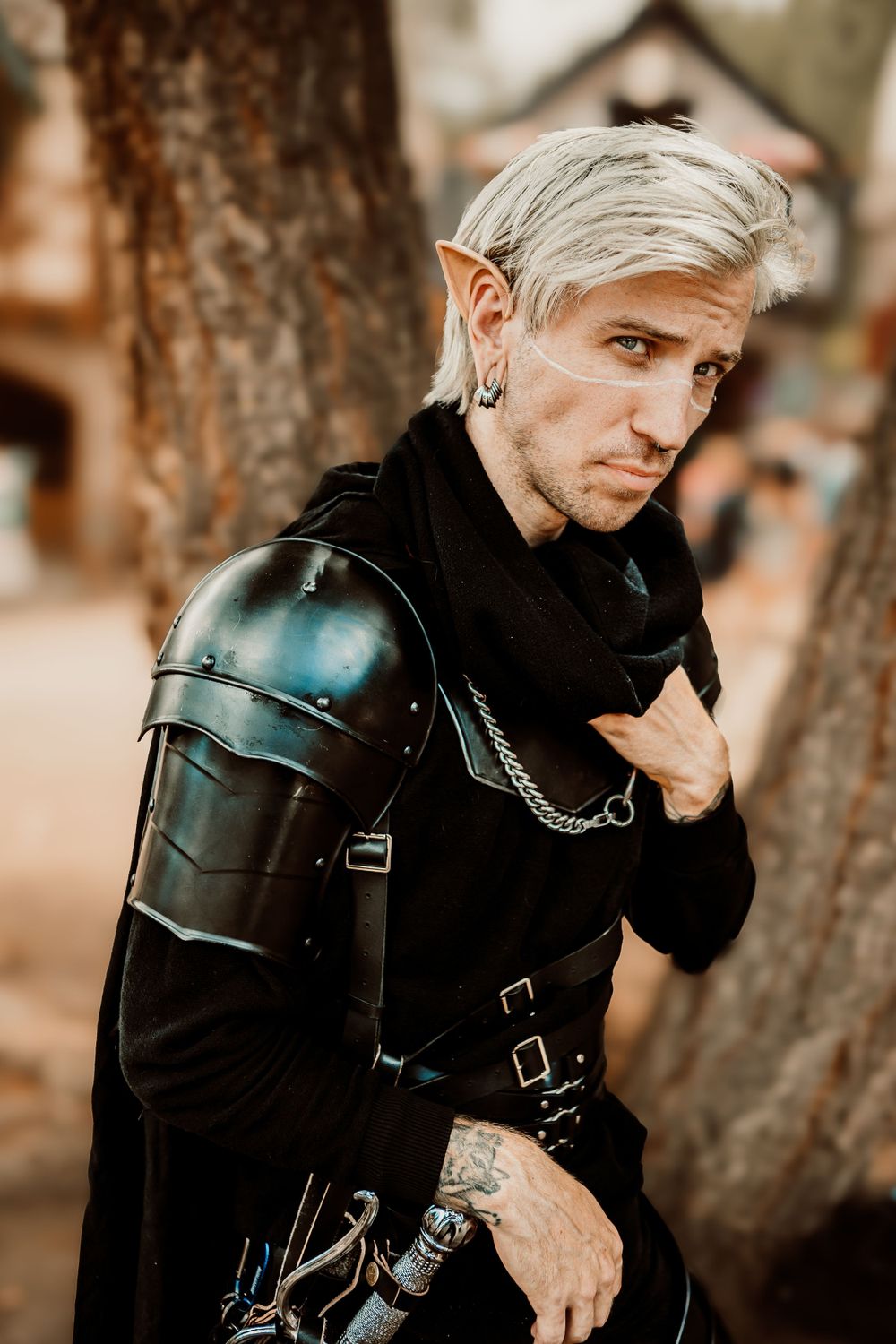 Fantasy cosplay portrait featuring leather armor and silver hair against rustic background.