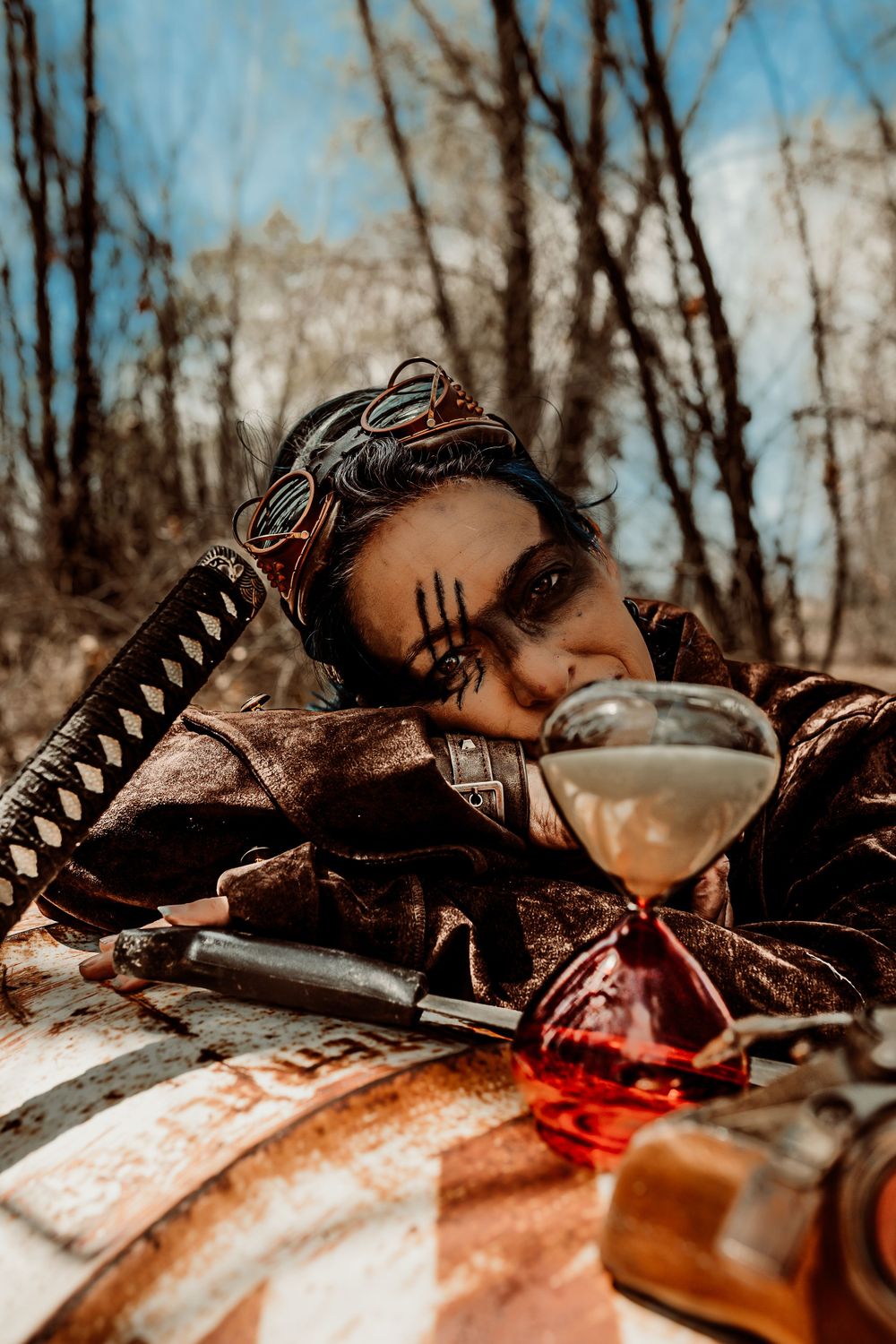 Post-apocalyptic themed image with decorated figure drinking from unique glassware outdoors.