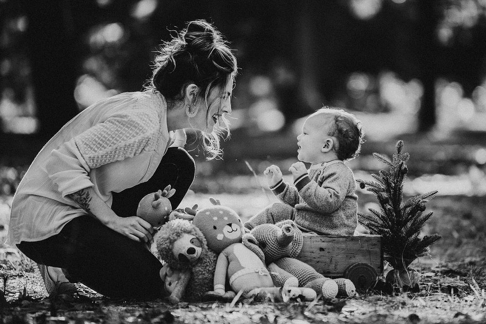 Black and white photo capturing joyful moments with stuffed toys in outdoor setting.