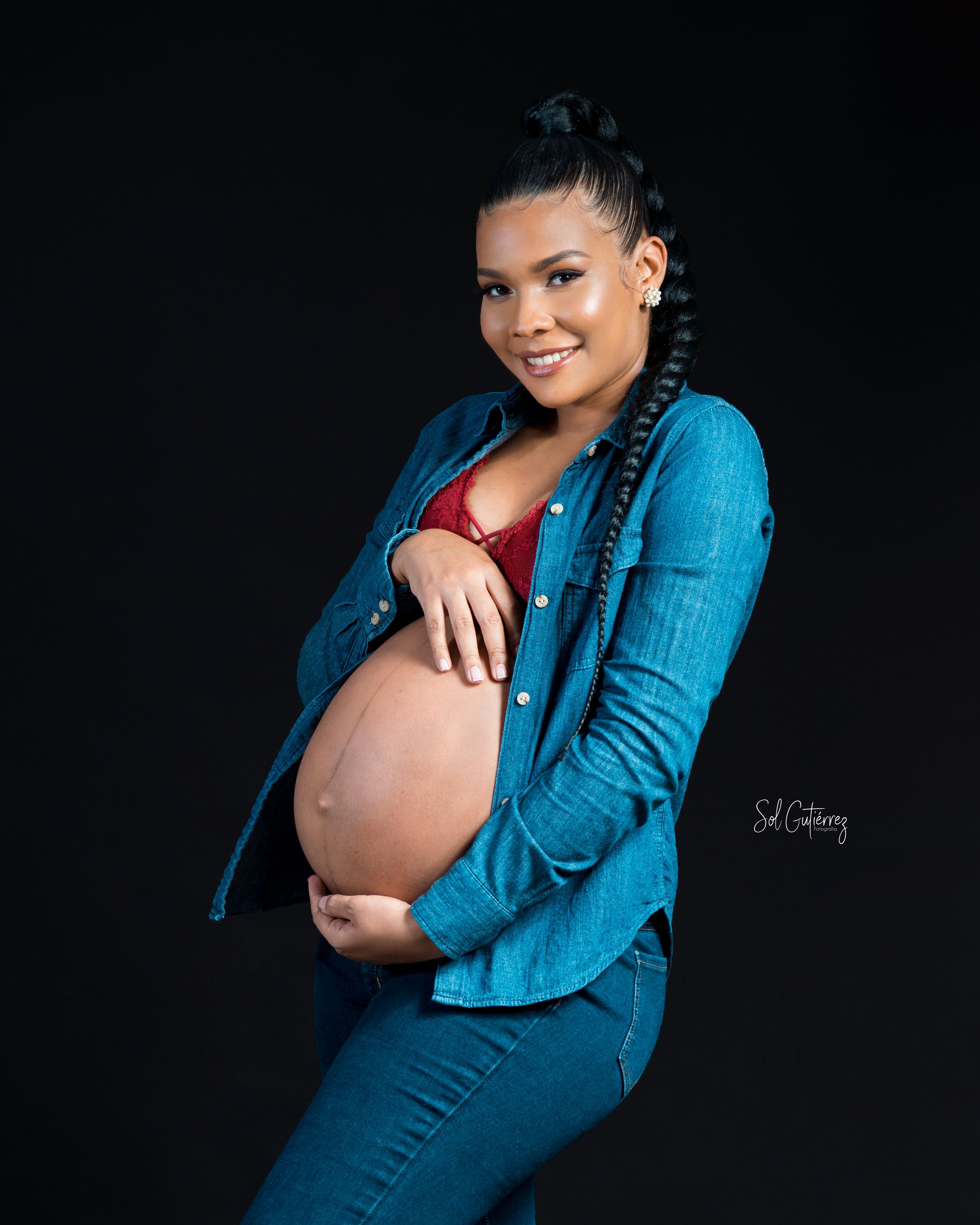 Maternity photoshoot in Allentown PA of pregnant woman smiling in studio with black background.