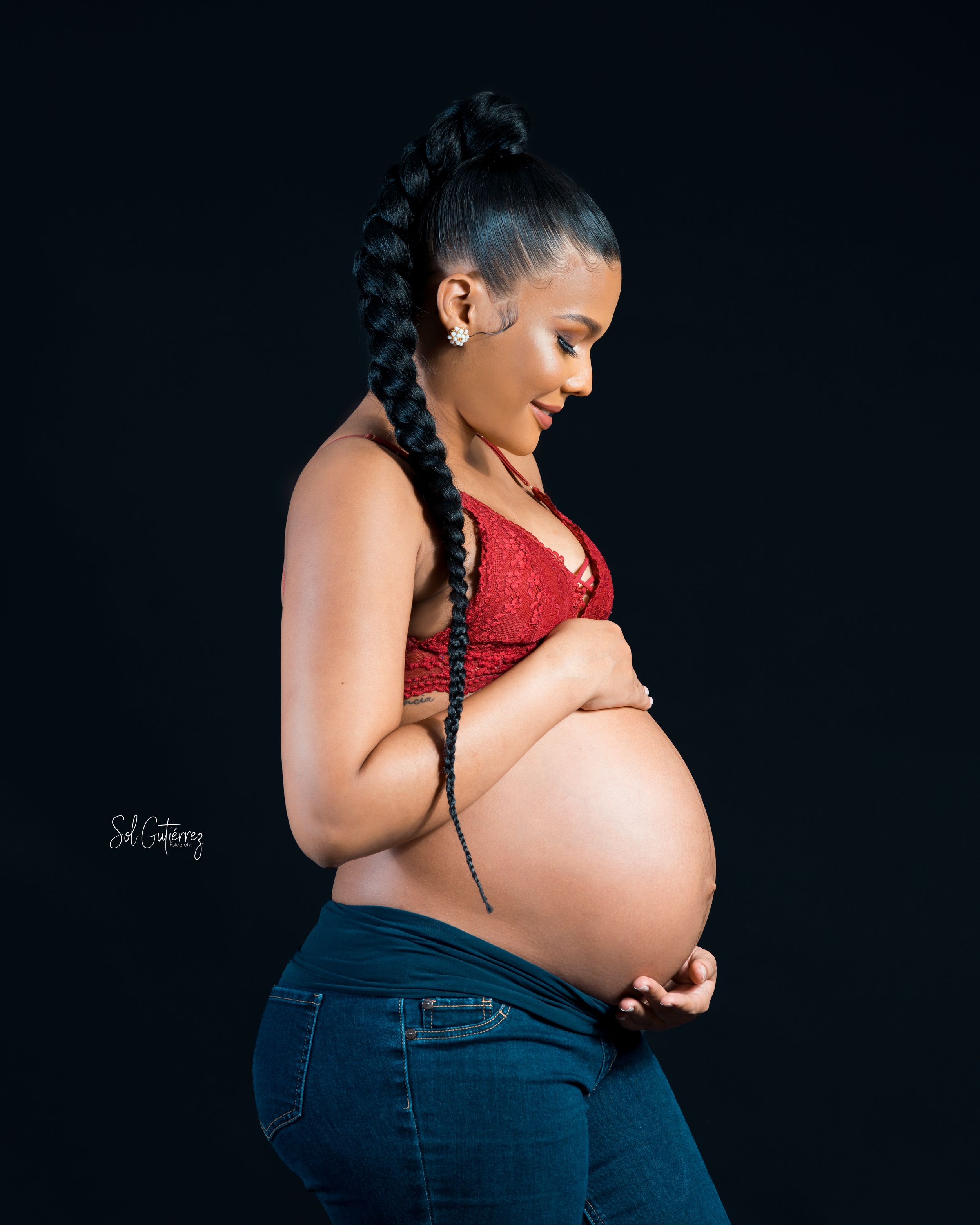 Studio maternity portrait in Allentown PA of pregnant woman holding belly with elegant side pose.