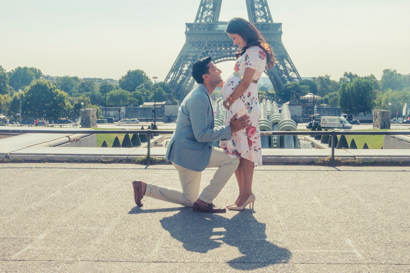A romantic couple on their babymoon sharing a tender moment together, posing in front of the Eiffel Tower