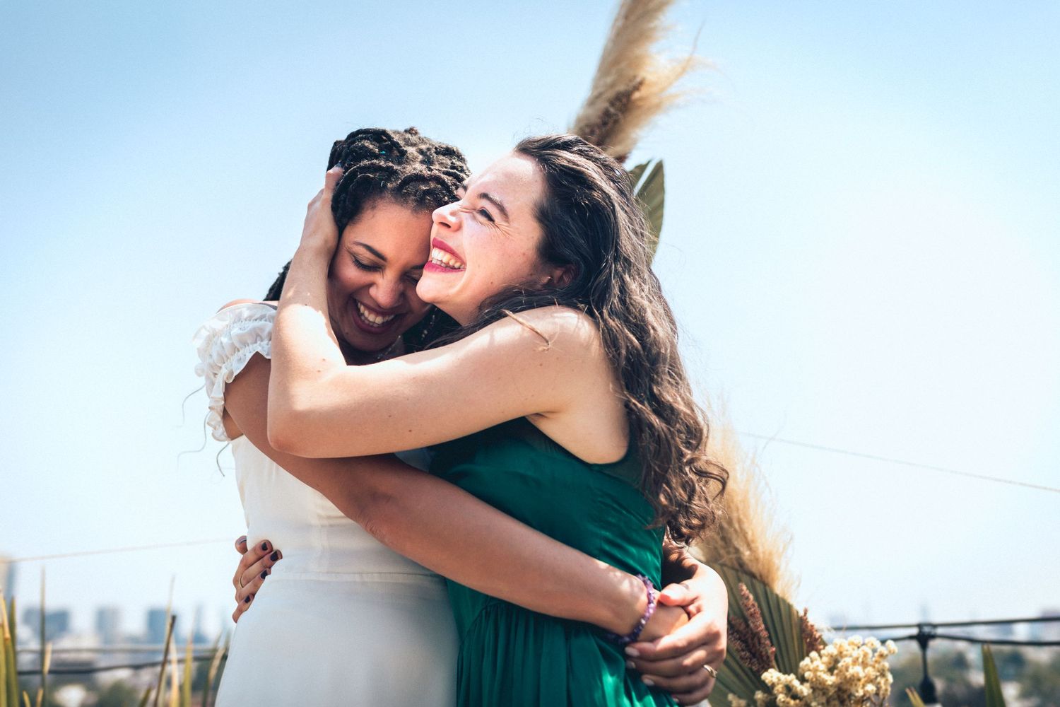 Candid moments of wedding party members embracing and laughing during outdoor celebration.