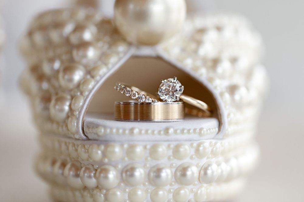 Diamond engagement ring and wedding bands displayed in decorative pearl crown-shaped jewelry box.