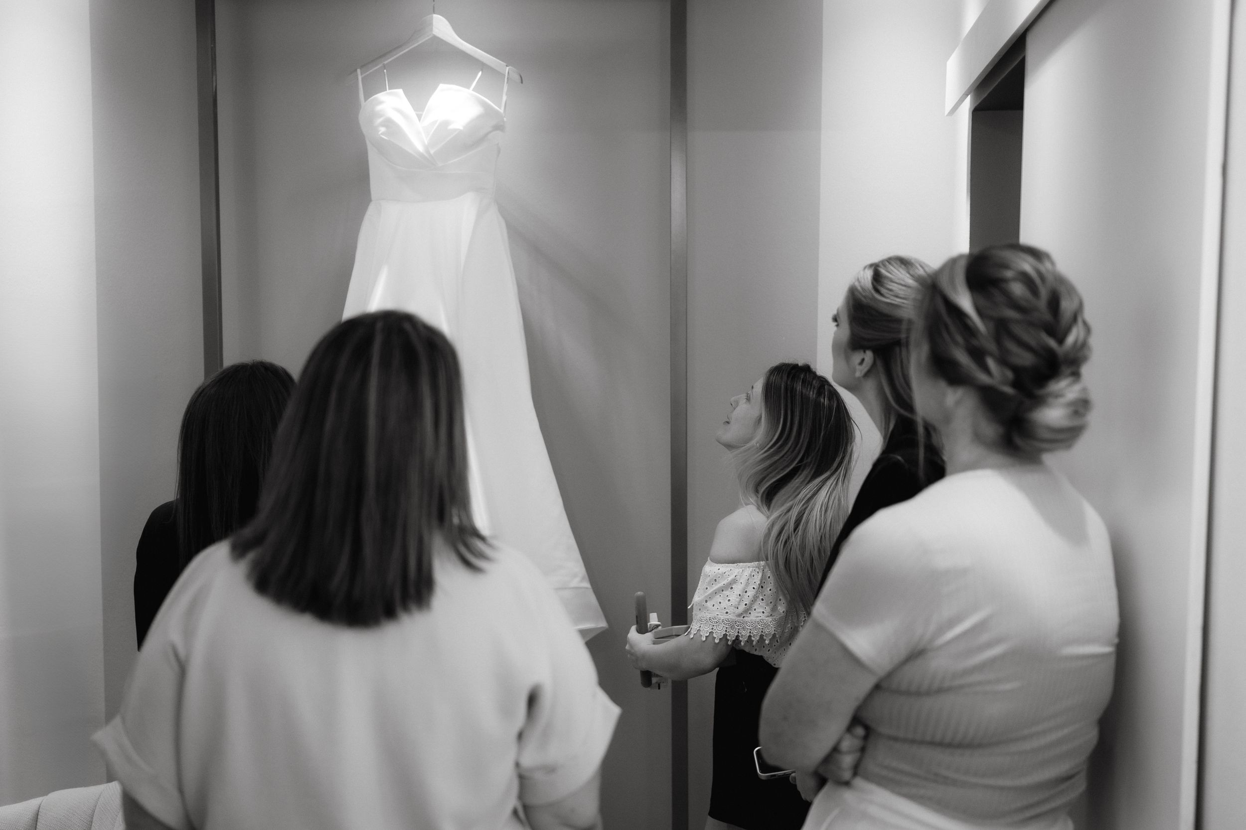 Behind-the-scenes preparation moments in a bridal dressing room with hanging gowns.