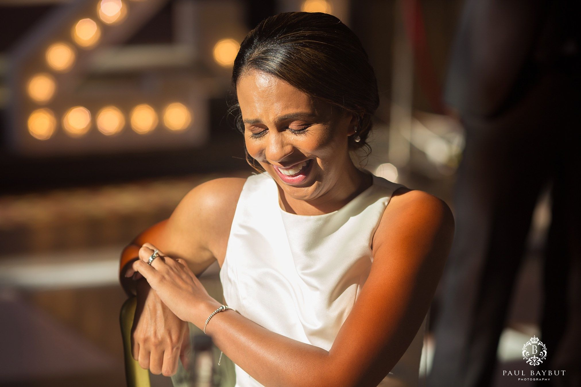 A candid moment of joyful laughter during a celebration with warm lighting in the background.