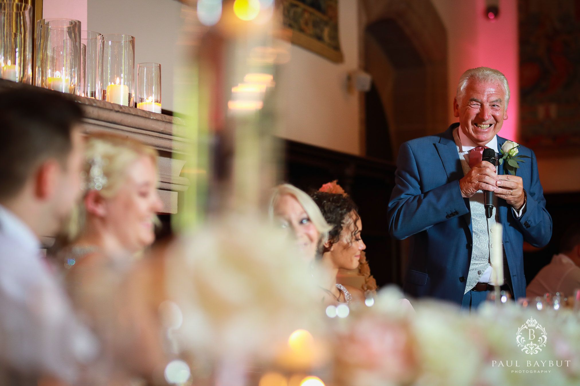 Wedding reception speech captured with warm ambient lighting and table decorations.
