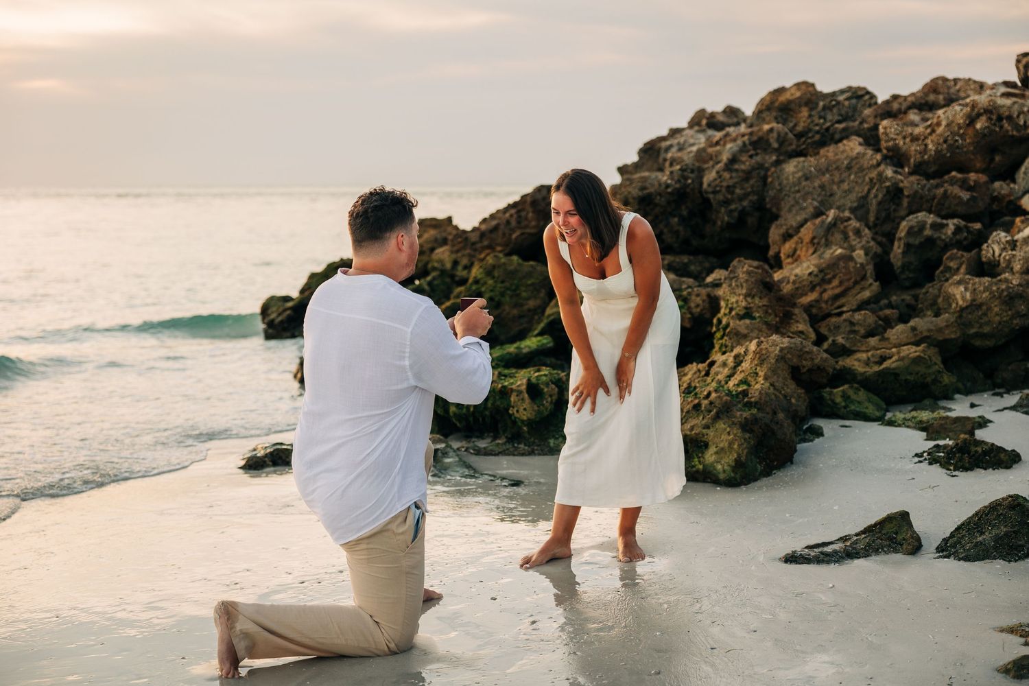 Man down on one knee proposing to his girlfriend on Siesta Key Beach at sunset taken by Sarasota Wedding Photographer.