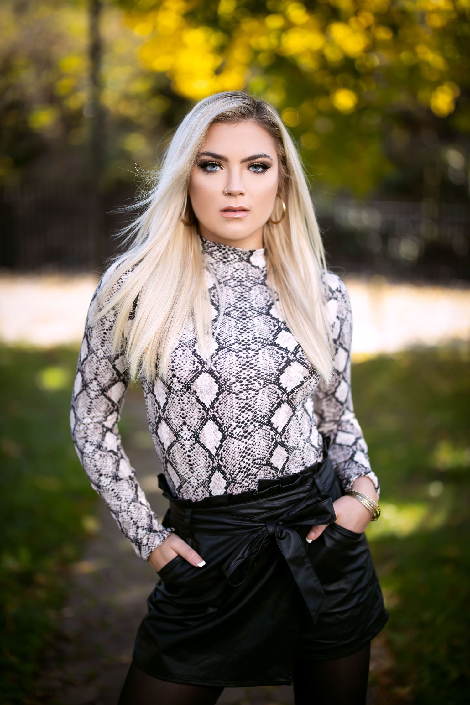 Outdoor fashion portrait in snakeskin print top with fall foliage background.