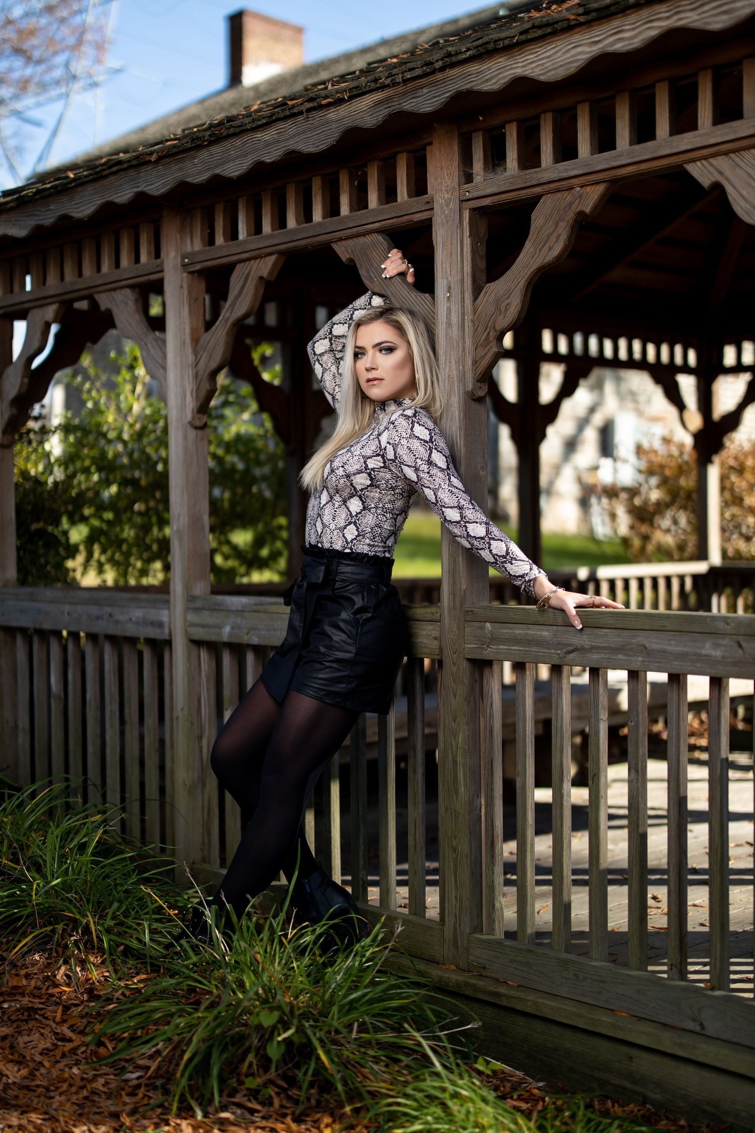 Full length fashion portrait at wooden gazebo wearing snakeskin print and black outfit.