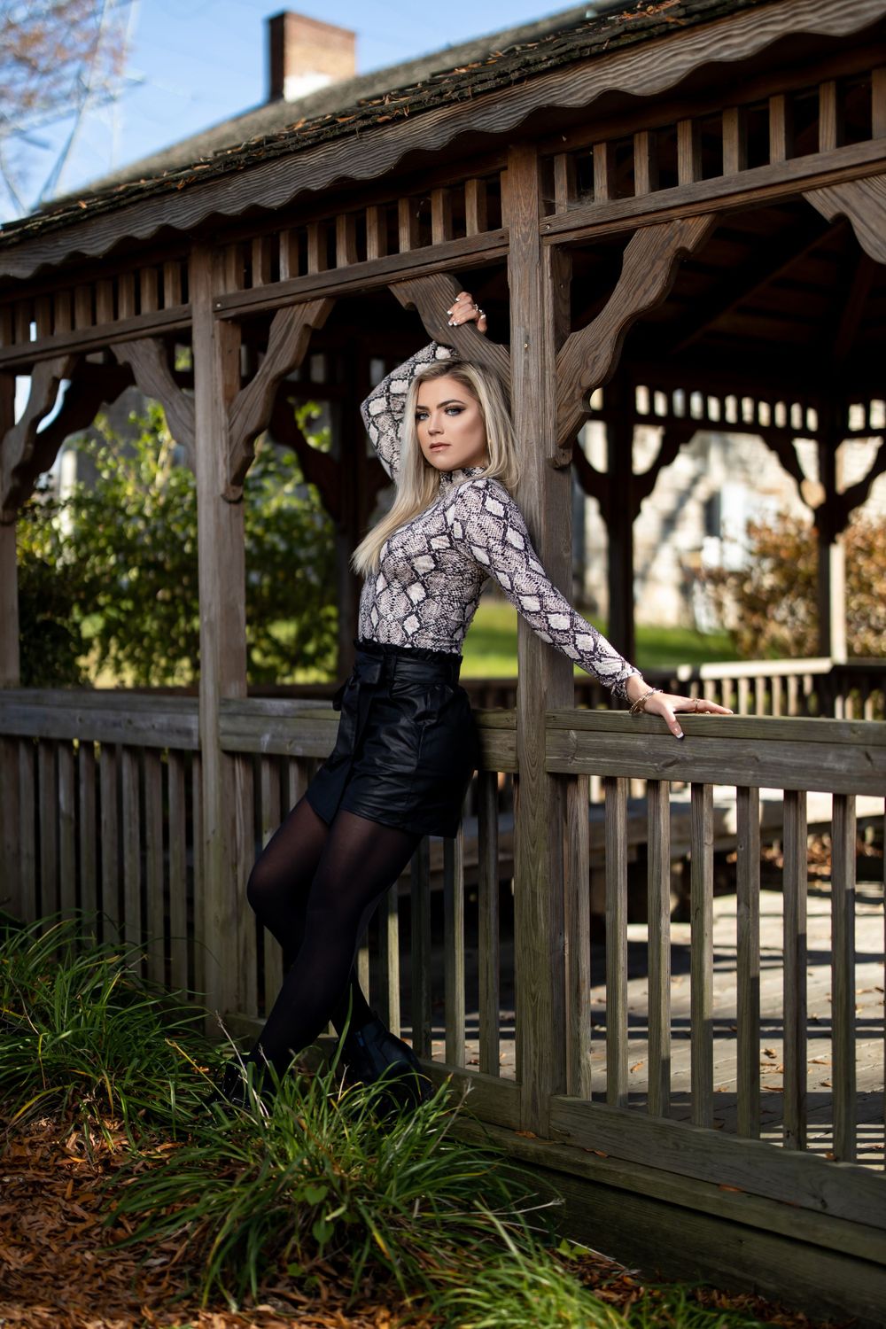 Full length fashion portrait at wooden gazebo wearing snakeskin print and black outfit.