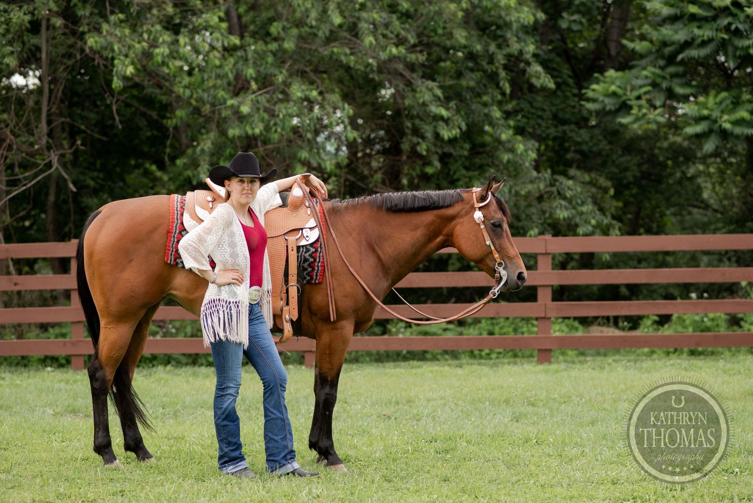 A brown horse with western saddle stands next to someone in casual attire.