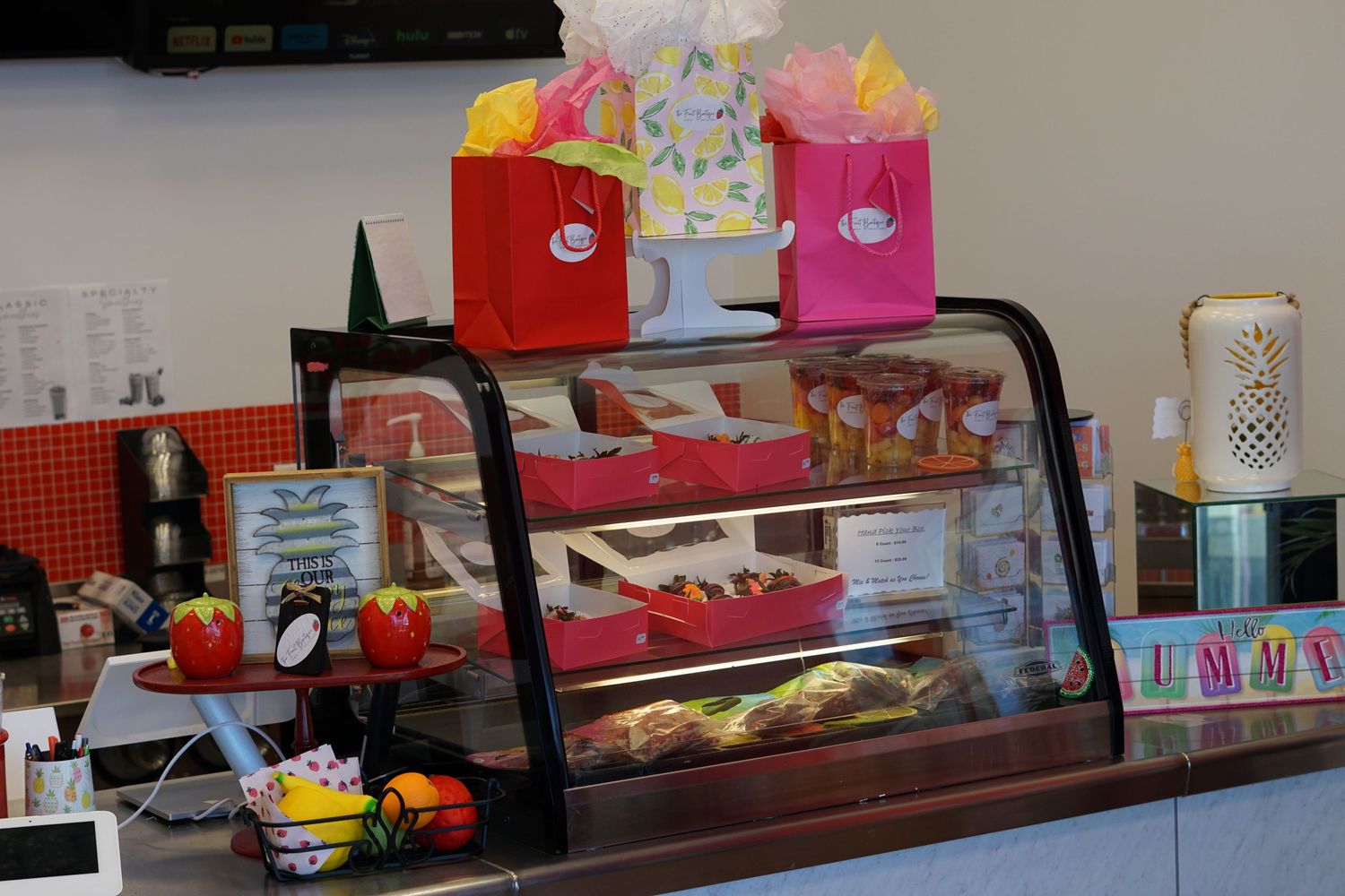 Glass bakery display case with colorful gift bags and fresh pastries at a cafe counter.