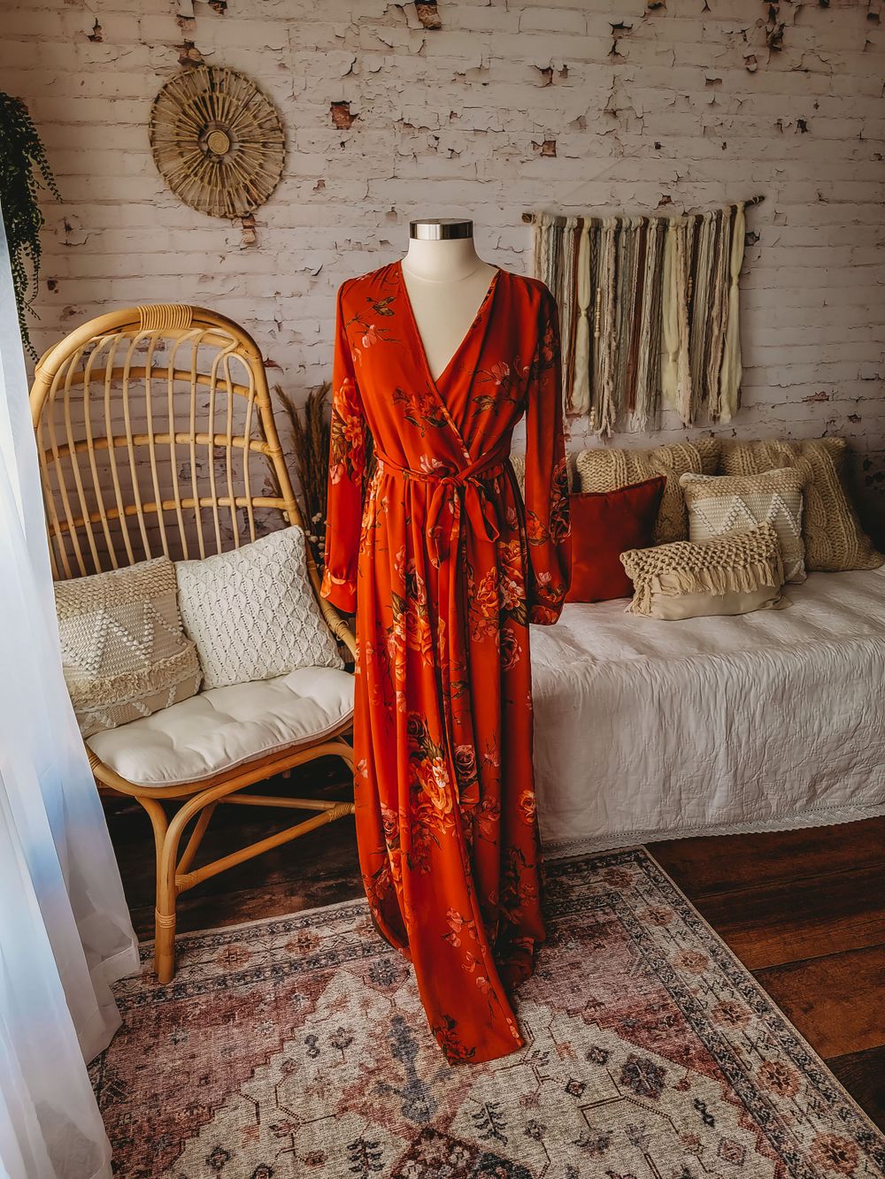 Burnt orange floral print wrap maxi dress with long sleeves on mannequin in boho room.
