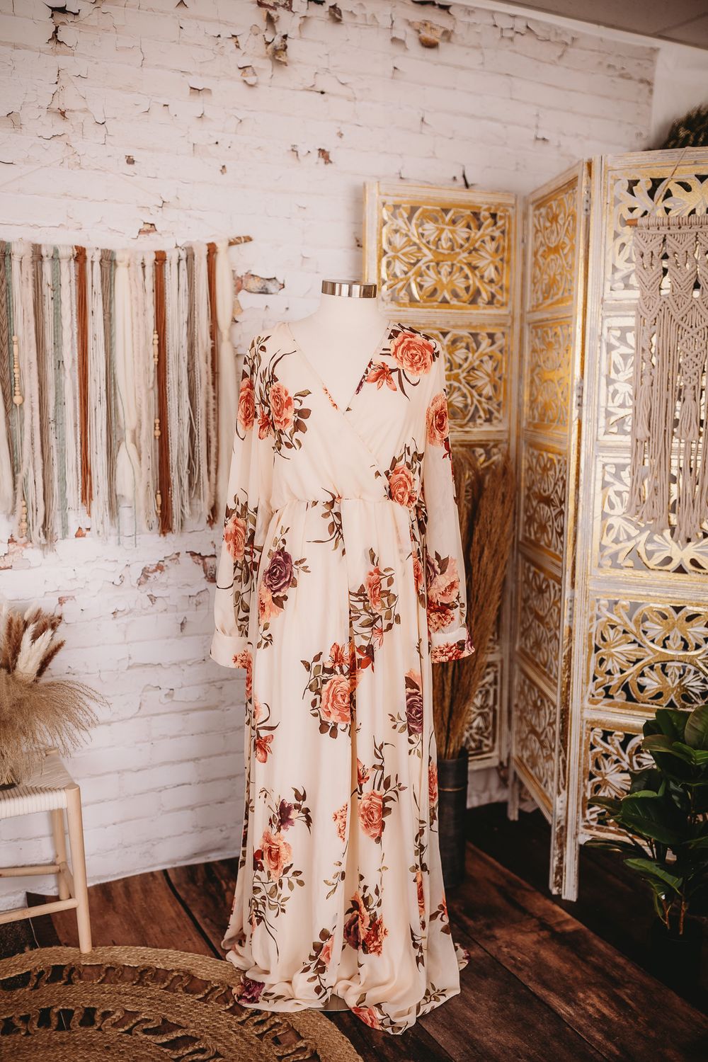 Cream floral print long sleeve maxi dress with V-neckline displayed on mannequin in boho setting.