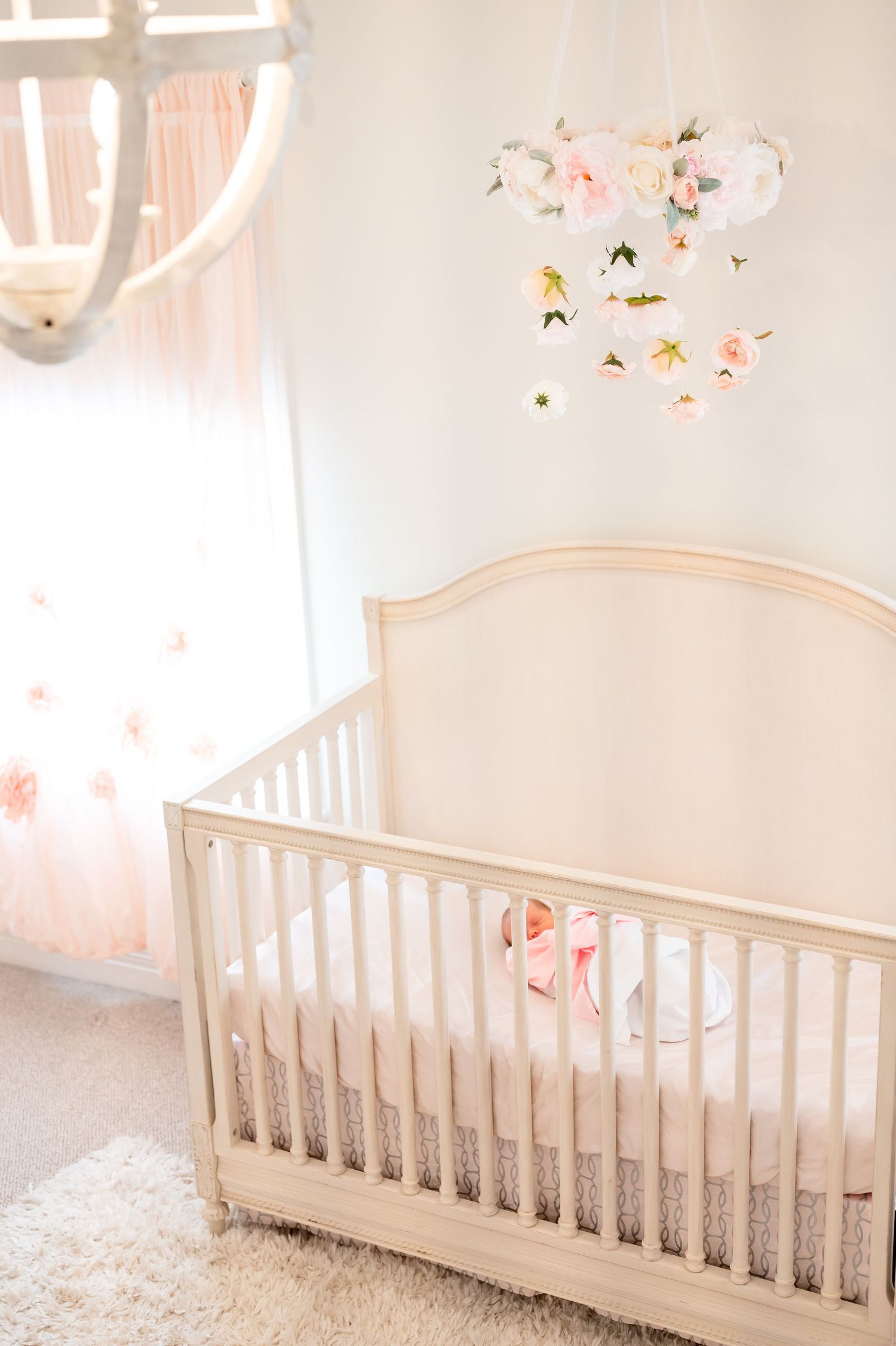 newborn baby girl sleeping in her crib during a natural light newborn lifestyle in home photography session in houston