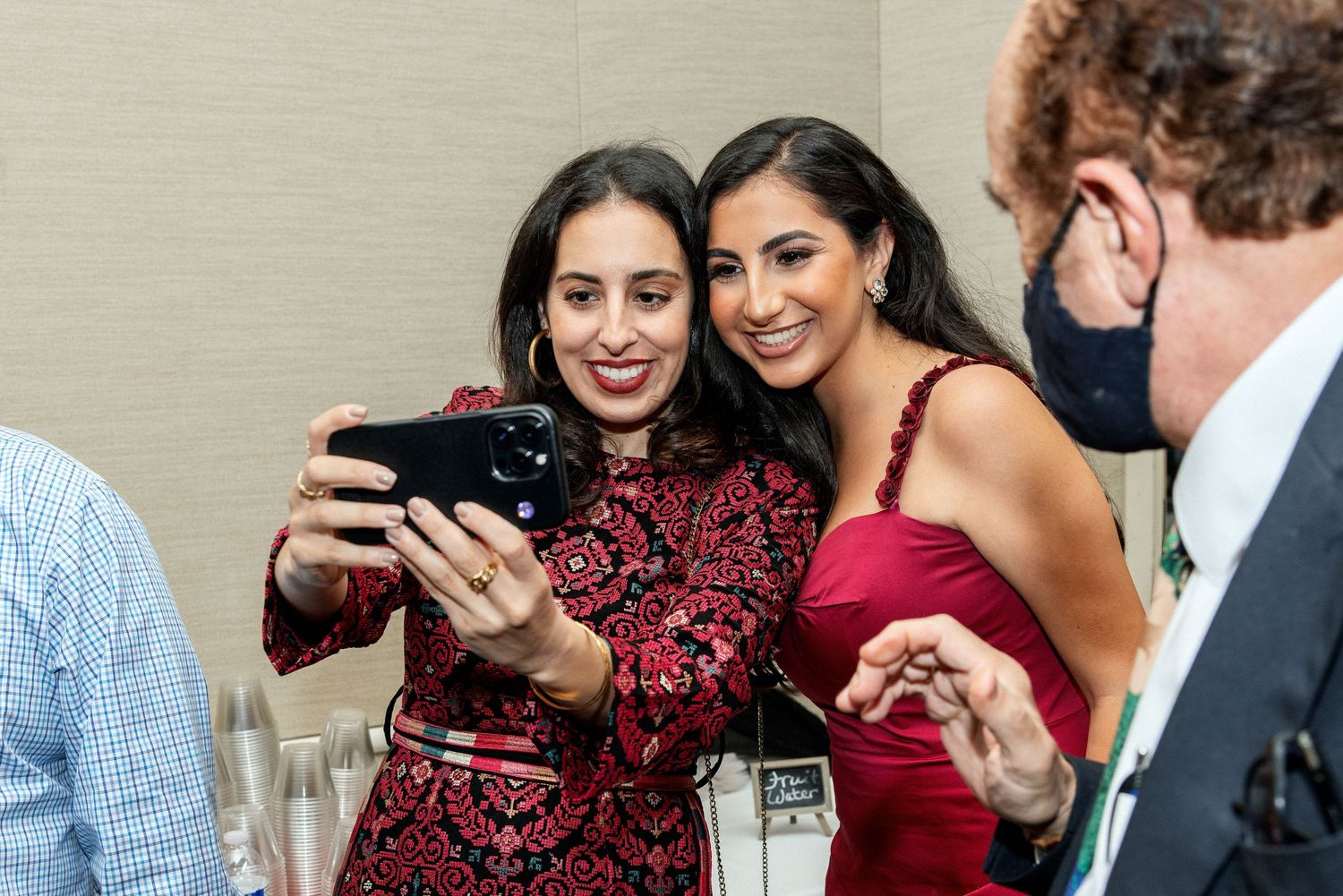 Wedding guests looking at photos on a phone during a celebration.