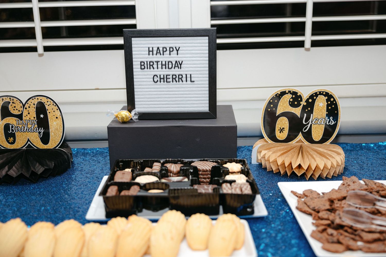 A 60th birthday party dessert table with black and gold decorations and a sign reading Happy Birthday.