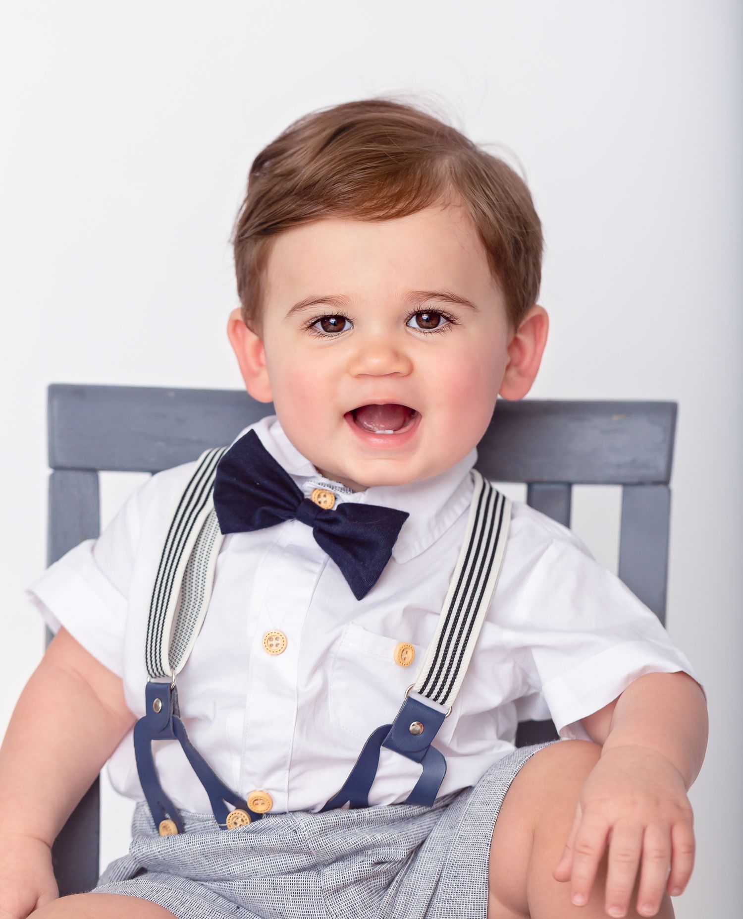 Baby wearing formal white outfit with suspenders and bow tie in multiple poses.
Kids.