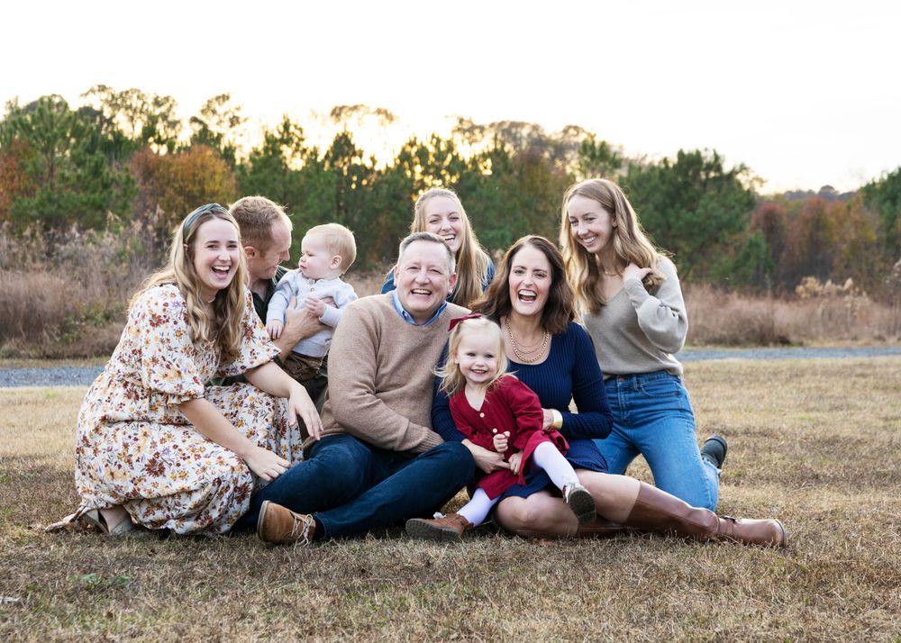A three generation family posing together on the grass in the park for Christmas season photo shoot.